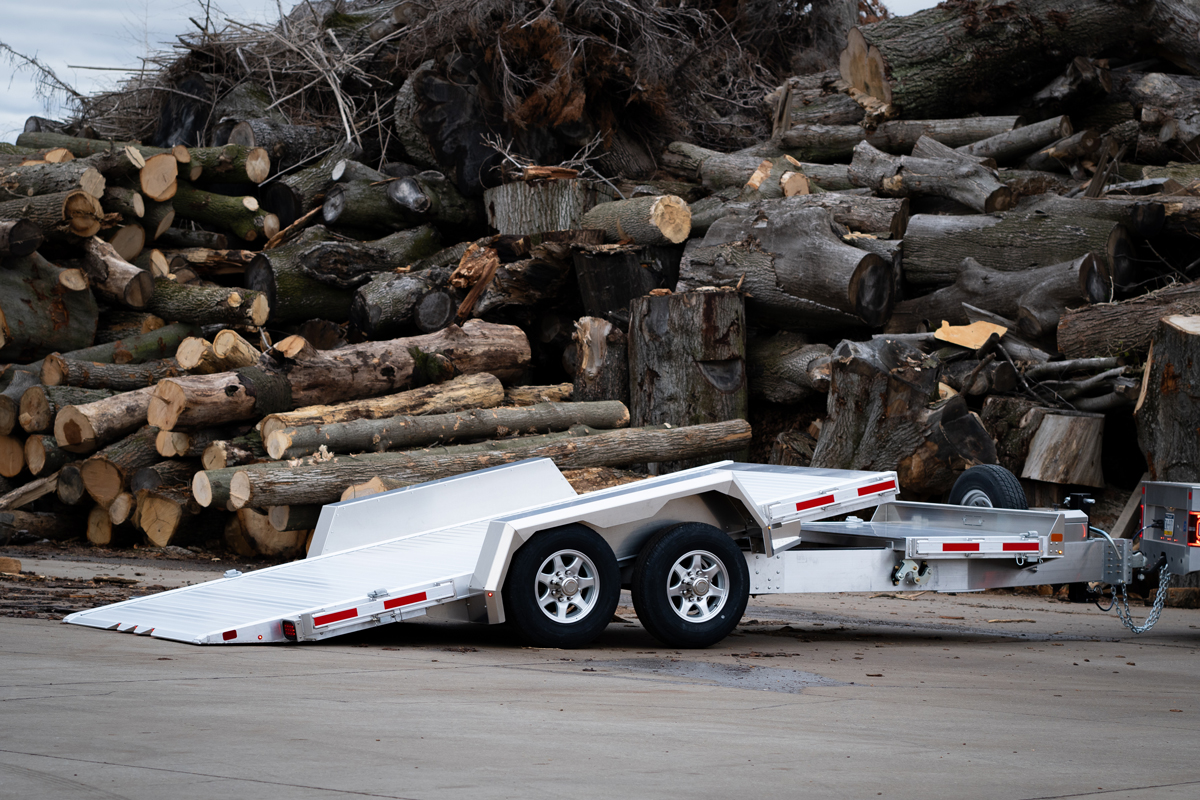 Tilt trailer infront of a log pile